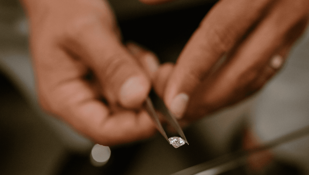 hands holding diamond in tweezers, showing diamond cut color clarity