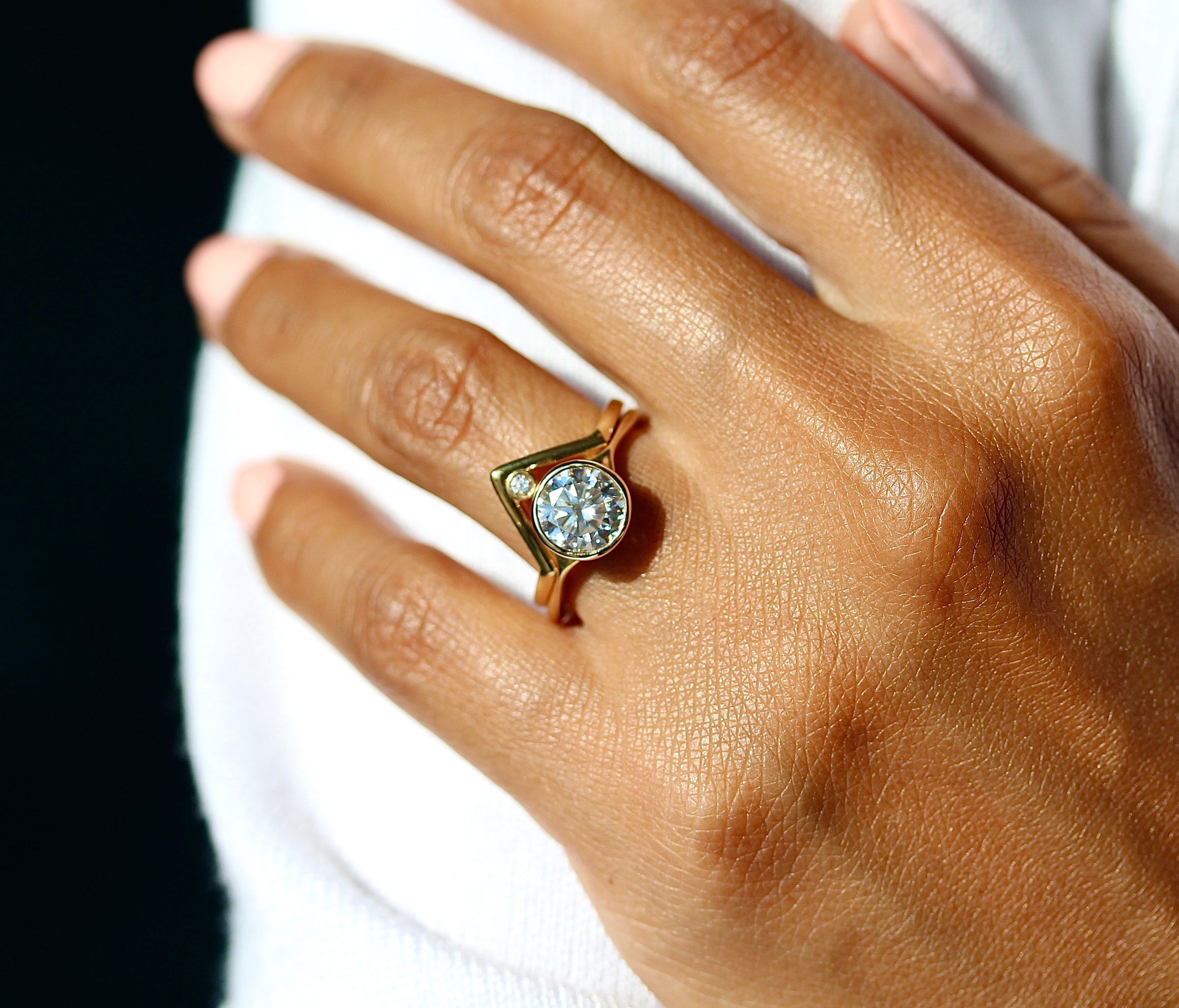 The Stevie Ring (Round) in yellow gold stacked with the Single Diamond V-Band in yellow gold modeled on a hand