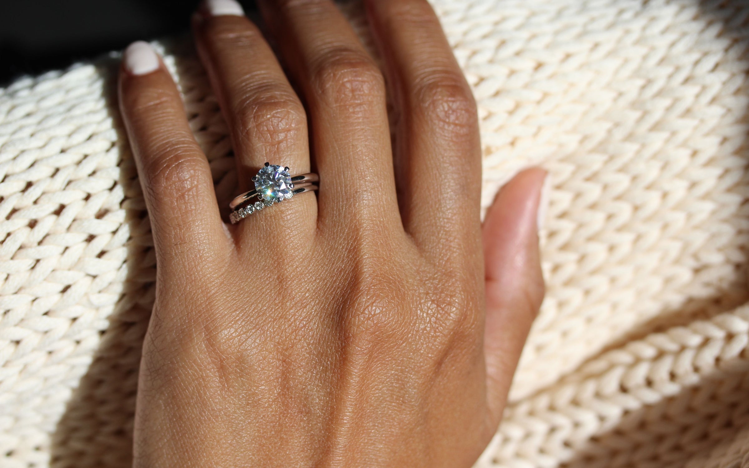 The Stevie Ring (Round) in white gold stacked with the Lexington Wedding Band in white gold modeled on a hand