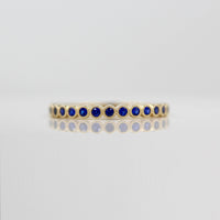 The September Florence Birthstone Wedding Band with Blue Sapphire in Yellow Gold against a white background