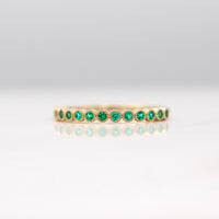 The May Florence Birthstone Wedding Band with Emerald in Yellow Gold against a white background