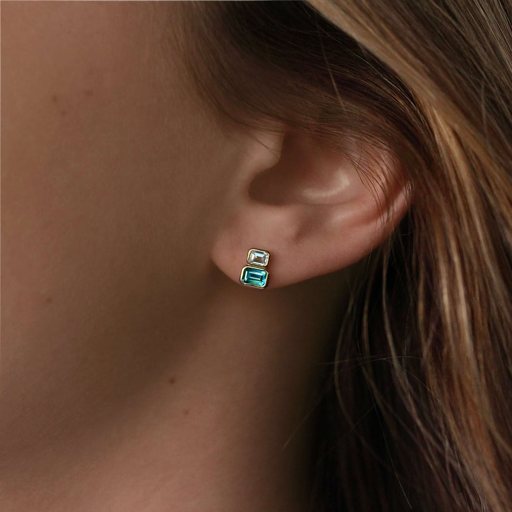 The Emerald-Cut Diamond and Paraiba Spinel Two-Stone Earrings in Yellow Gold modeled