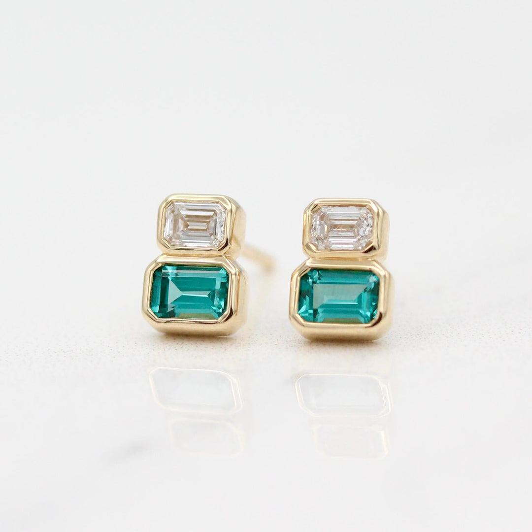 The Emerald-Cut Diamond and Paraiba Spinel Two-Stone Earrings in Yellow Gold against a white background