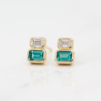 The Emerald-Cut Diamond and Paraiba Spinel Two-Stone Earrings in Yellow Gold against a white background