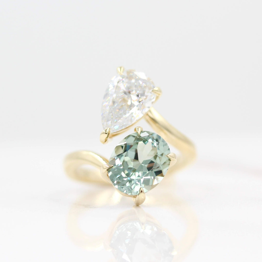 Engagement Ring 14k Yellow Gold Toi Et Moi Diamond and Sage Green Sapphire Bypass Ring in Yellow Gold against a white background