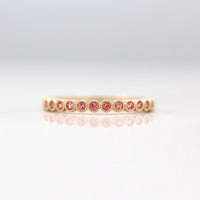 The January Florence Birthstone Wedding Band with Padparadscha Sapphire in Yellow Gold against a white background