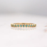 The December Florence Birthstone Wedding Band with Paraiba Spinel in Yellow Gold against a white background