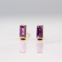 The February Baguette Birthstone Earrings with Purple Sapphire in Yellow Gold against a white background