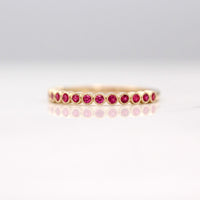 The July Florence Birthstone Wedding Band with Ruby in Yellow Gold against a white background
