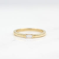 a gold baguette ring on a white surface
