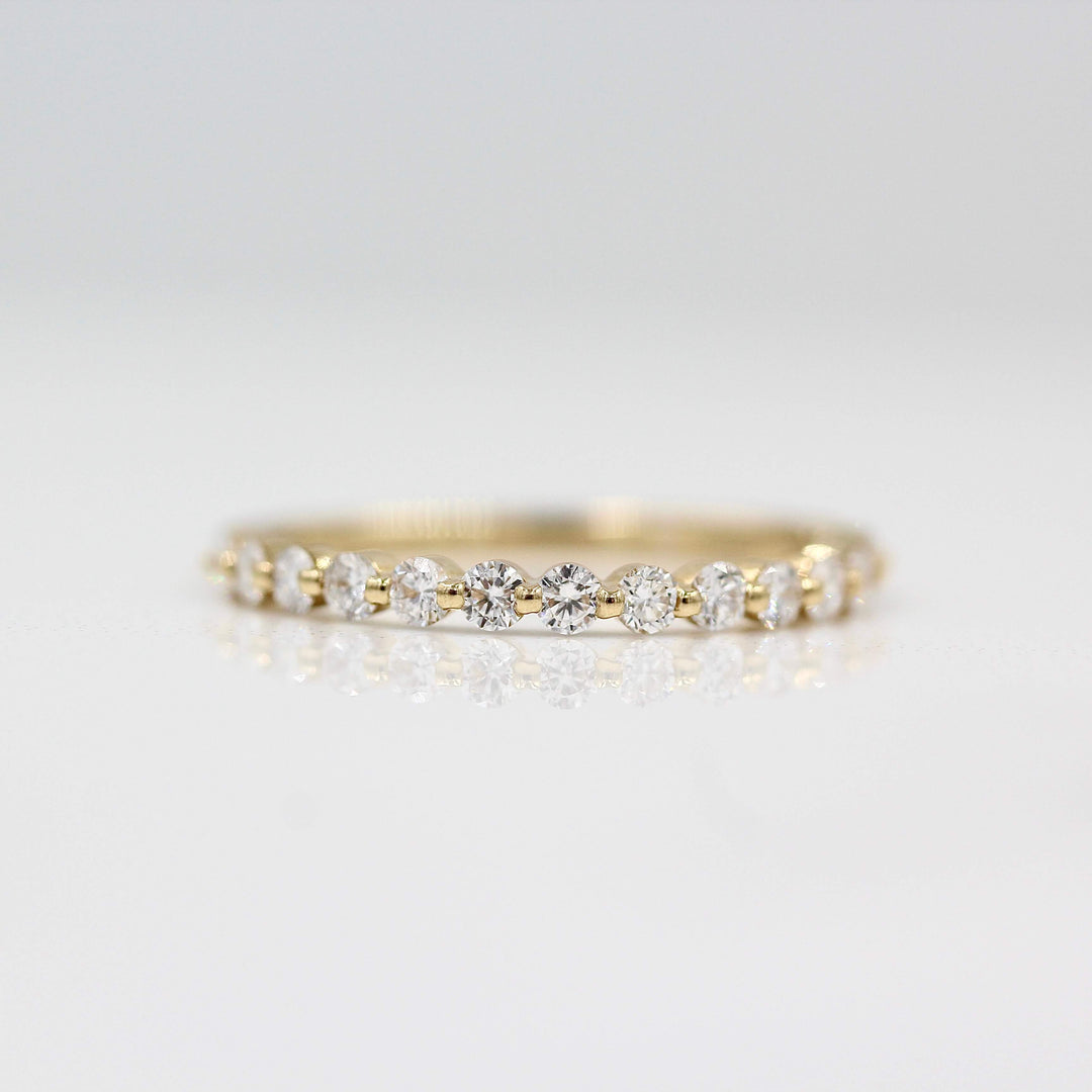 a gold diamond wedding band on a white surface