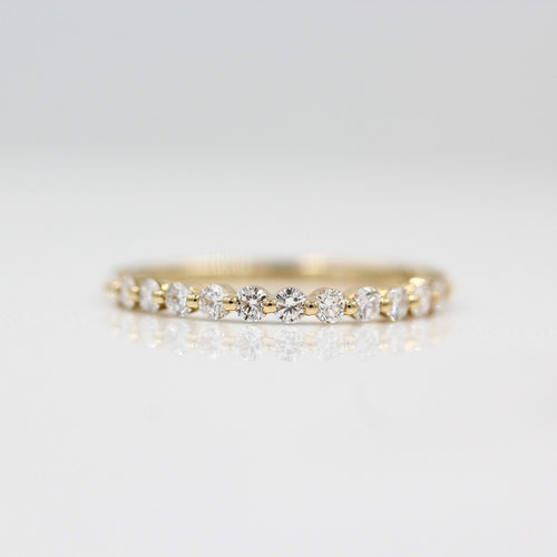 a gold diamond wedding band on a white surface