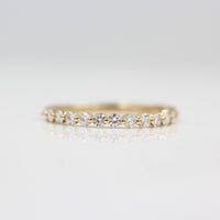 a gold diamond wedding band on a white surface
