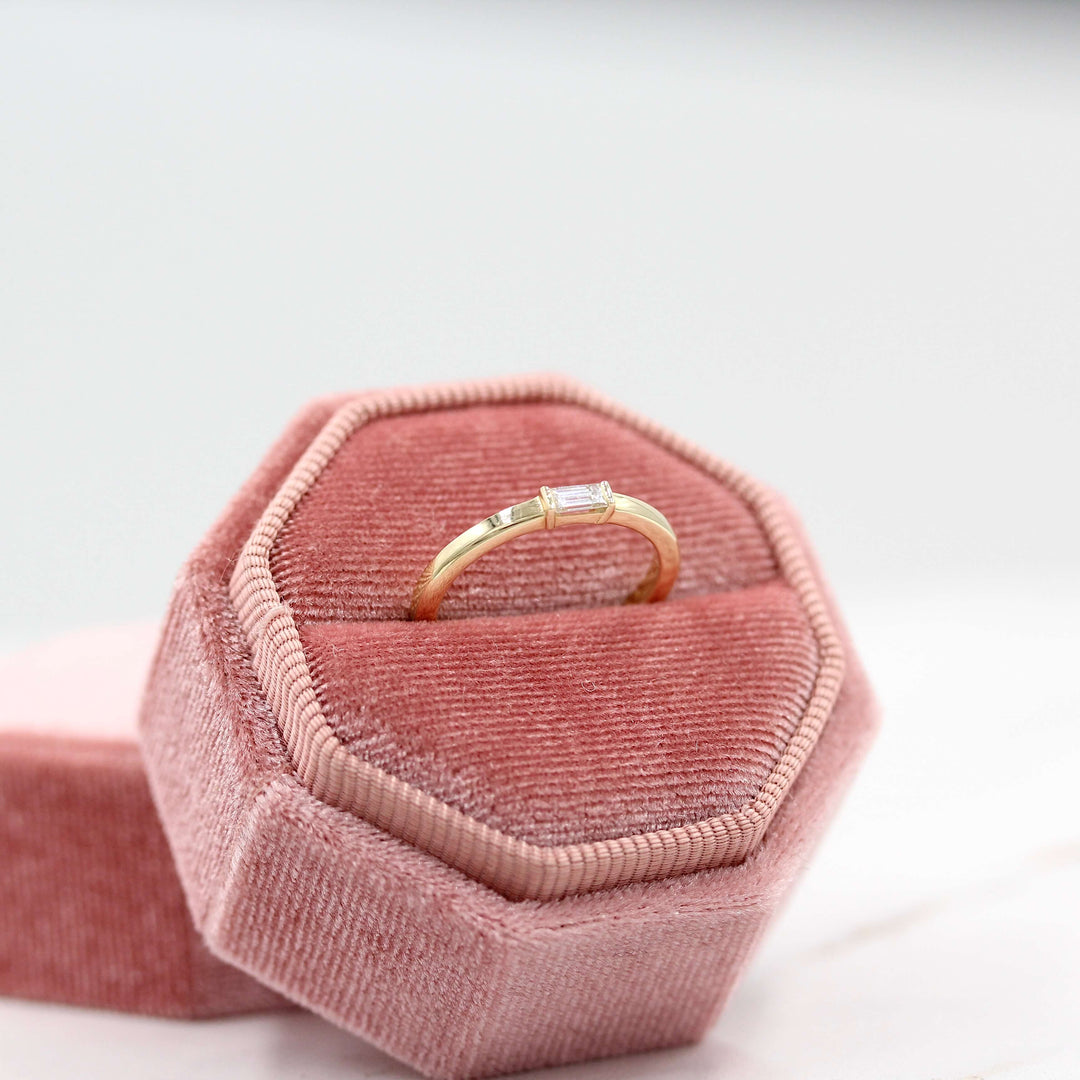 a gold baguette ring in a pink ring box