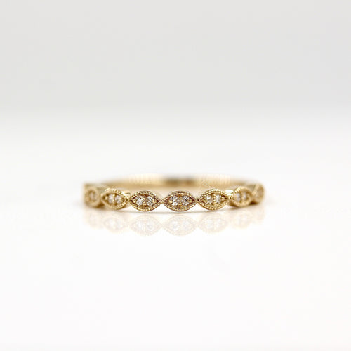 a gold scalloped wedding band on a white surface
