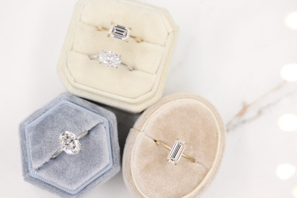 three engagement rings in various color ring boxes