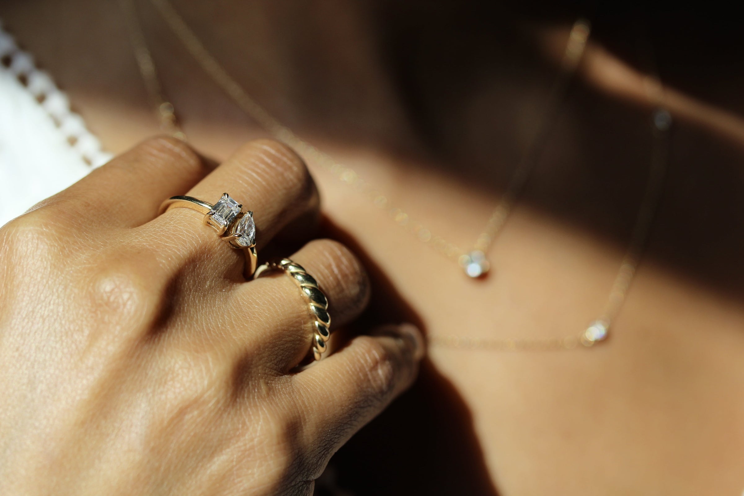 woman's hand with toi et moi ring and petite croissant ring touching lab grown diamond necklaces