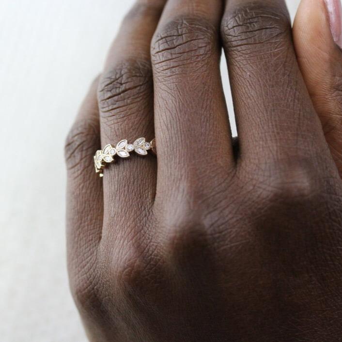 Intricate floral wedding band in 14k yellow gold modeled on a hand