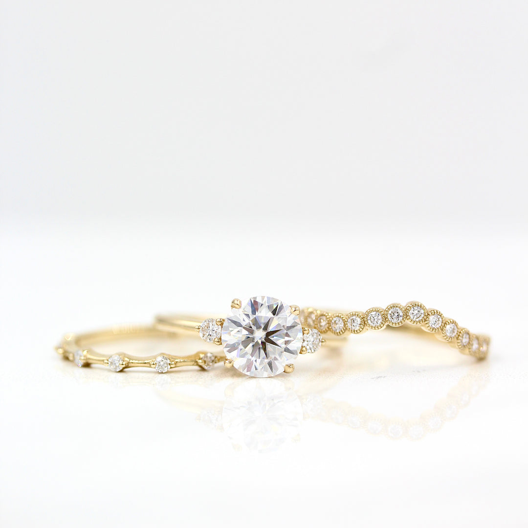 The Esme Ring (Round) in Yellow Gold with 2ct Moissanite staggered with the Florence Contour Band in yellow gold and the Sloane Wedding Band in yellow gold against a white background