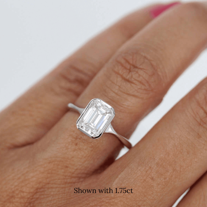 Hand wearing emerald-cut lab-grown diamond in a delicate white gold bezel ring