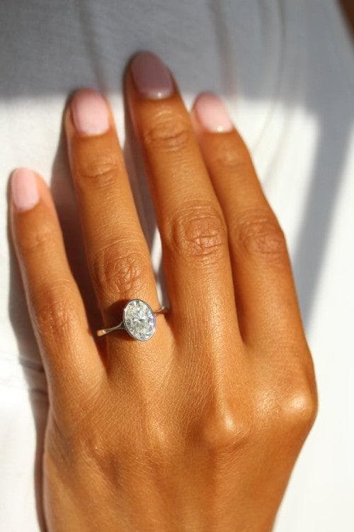 2ct oval Stevie bezel engagement ring on a hand