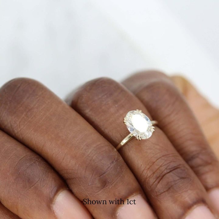 The Serena Ring (Oval) in yellow gold modeled on a hand with a dark complexion