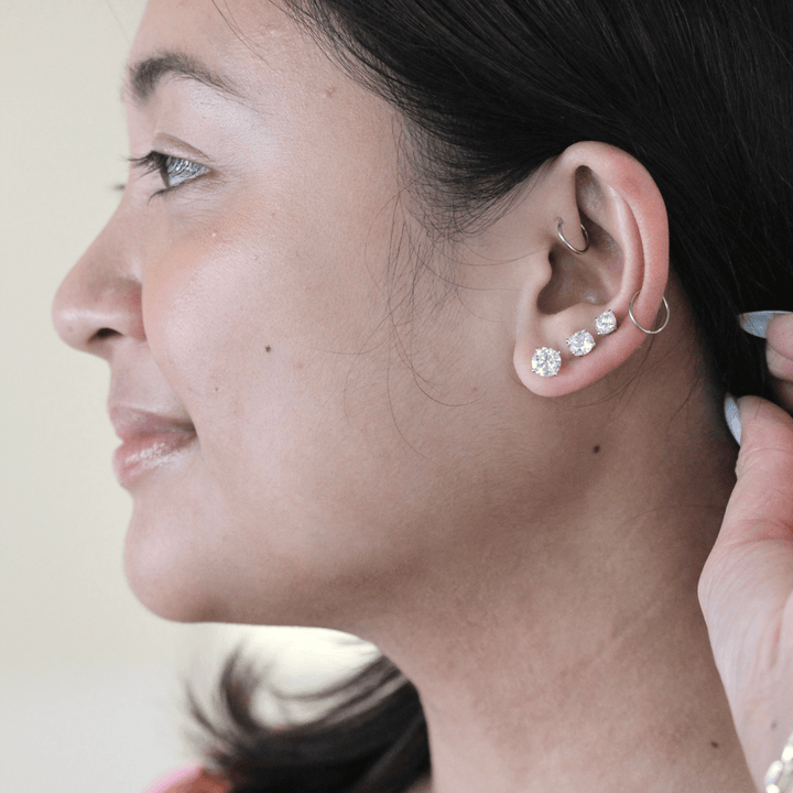 3 different sizes of diamond studs shown on persons ear 