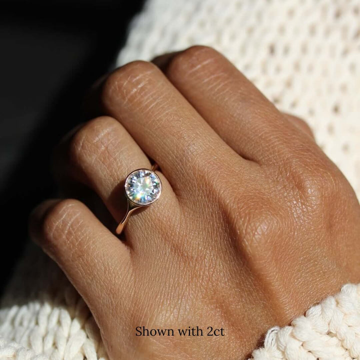2ct round bezel engagement ring modeled on a hand in natural light