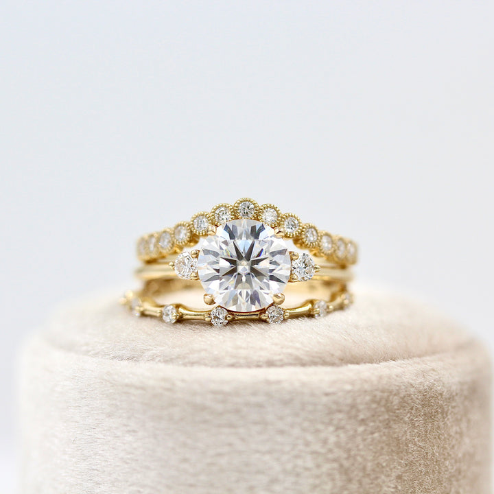 The Esme Ring (Round) in Yellow Gold with 2ct Moissanite stacked with the Florence Contour Band in yellow gold and the Sloane Wedding Band in yellow gold on a white velvet ring box