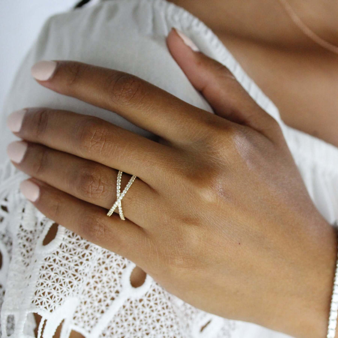 A hand resting on a shoulder, wearing a criss-cross lab-grown diamond ring