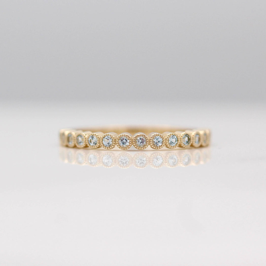 The March Florence Birthstone Wedding Band with Aqua Spinel in Yellow Gold against a white background