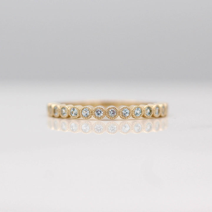 The March Florence Birthstone Wedding Band with Aqua Spinel in Yellow Gold against a white background