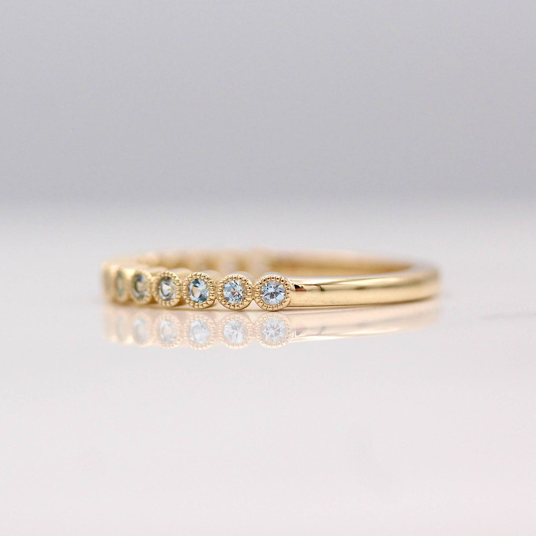 The March Florence Birthstone Wedding Band with Aqua Spinel in Yellow Gold against a white background