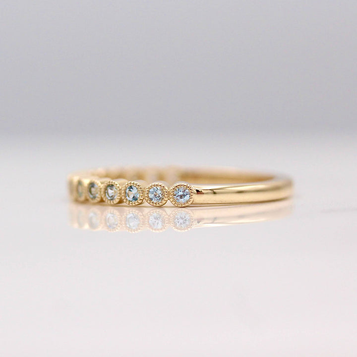 The March Florence Birthstone Wedding Band with Aqua Spinel in Yellow Gold against a white background