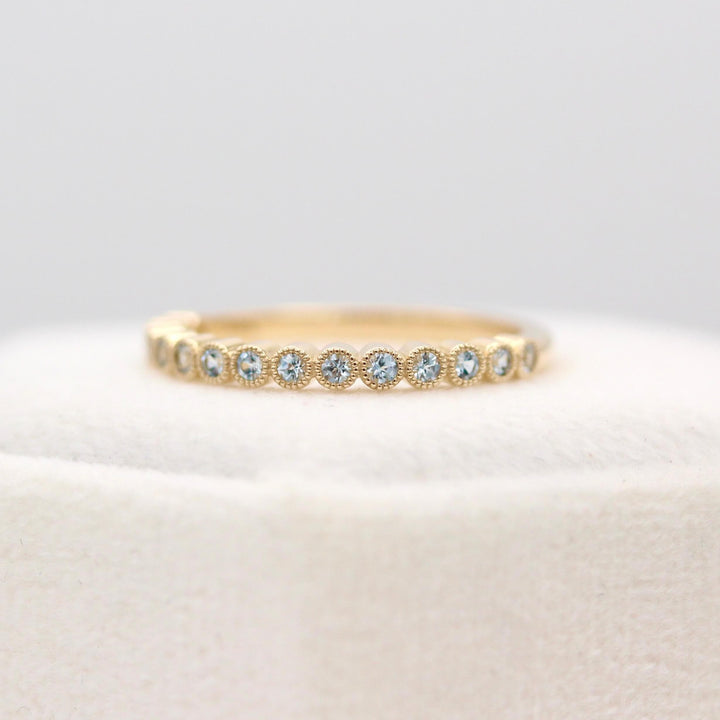 The March Florence Birthstone Wedding Band with Aqua Spinel in Yellow Gold atop of a white velvet ring box
