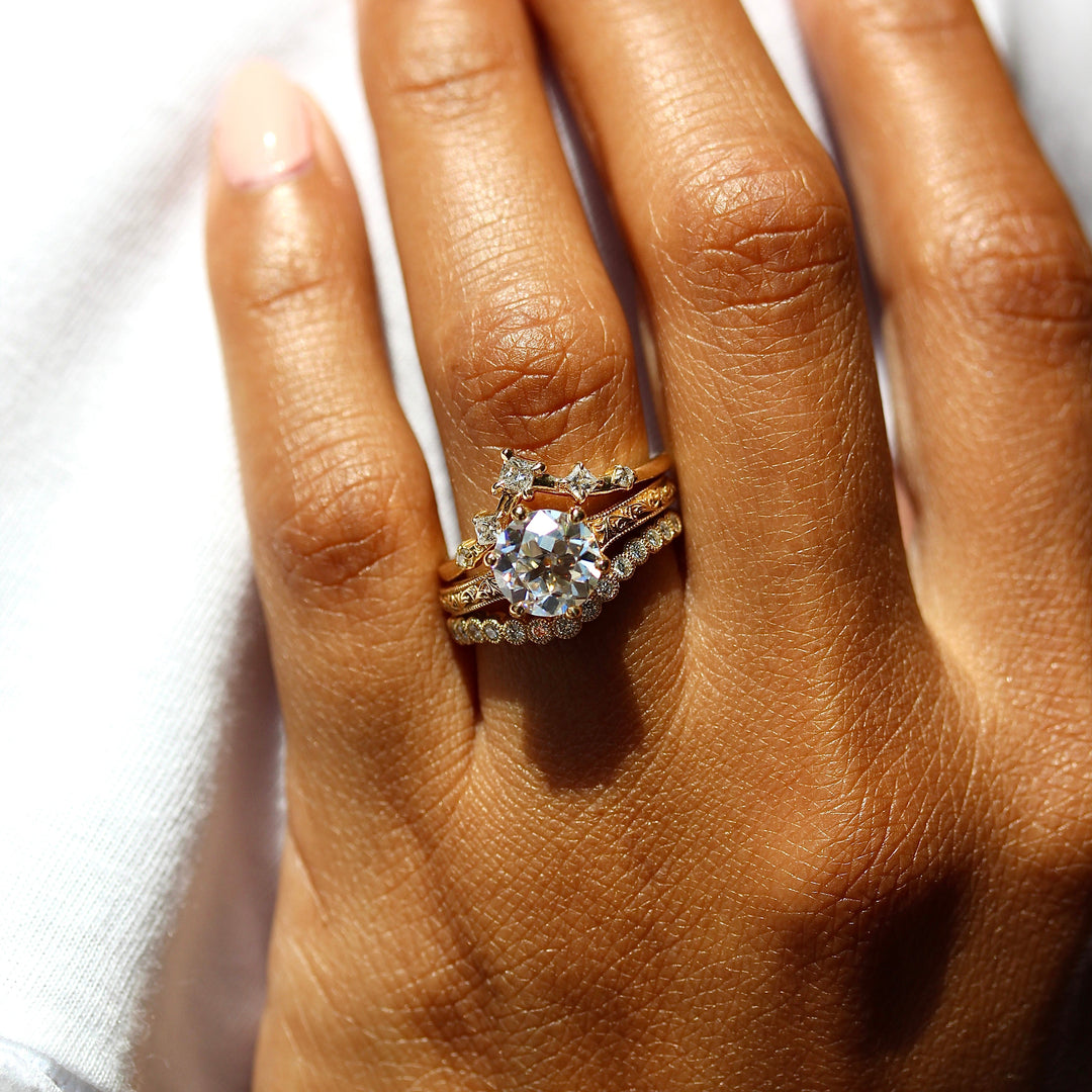 The Kathleen ring in yellow gold stacked with the Florence Contour wedding band in yellow gold and the Astra wedding band in yellow gold modeled on a hand