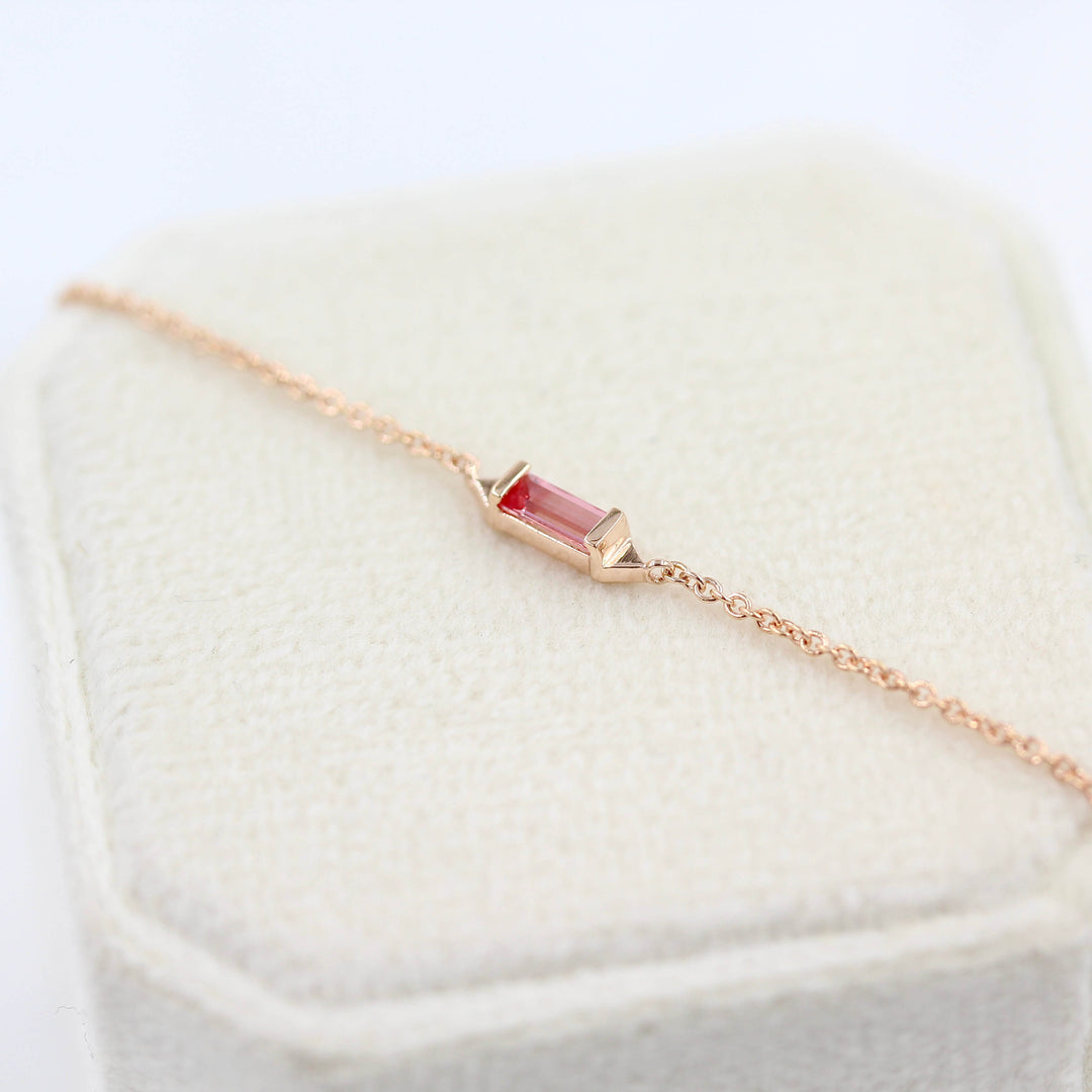 The Baguette Peachy-Pink Sapphire Necklace in Rose Gold atop a white velvet ring box