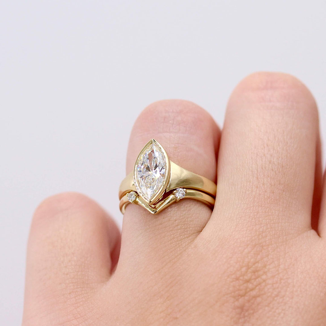 The Billie Ring (Marquise) in yellow gold modeled on a hand stacked with the Double Diamond V Band in yellow gold