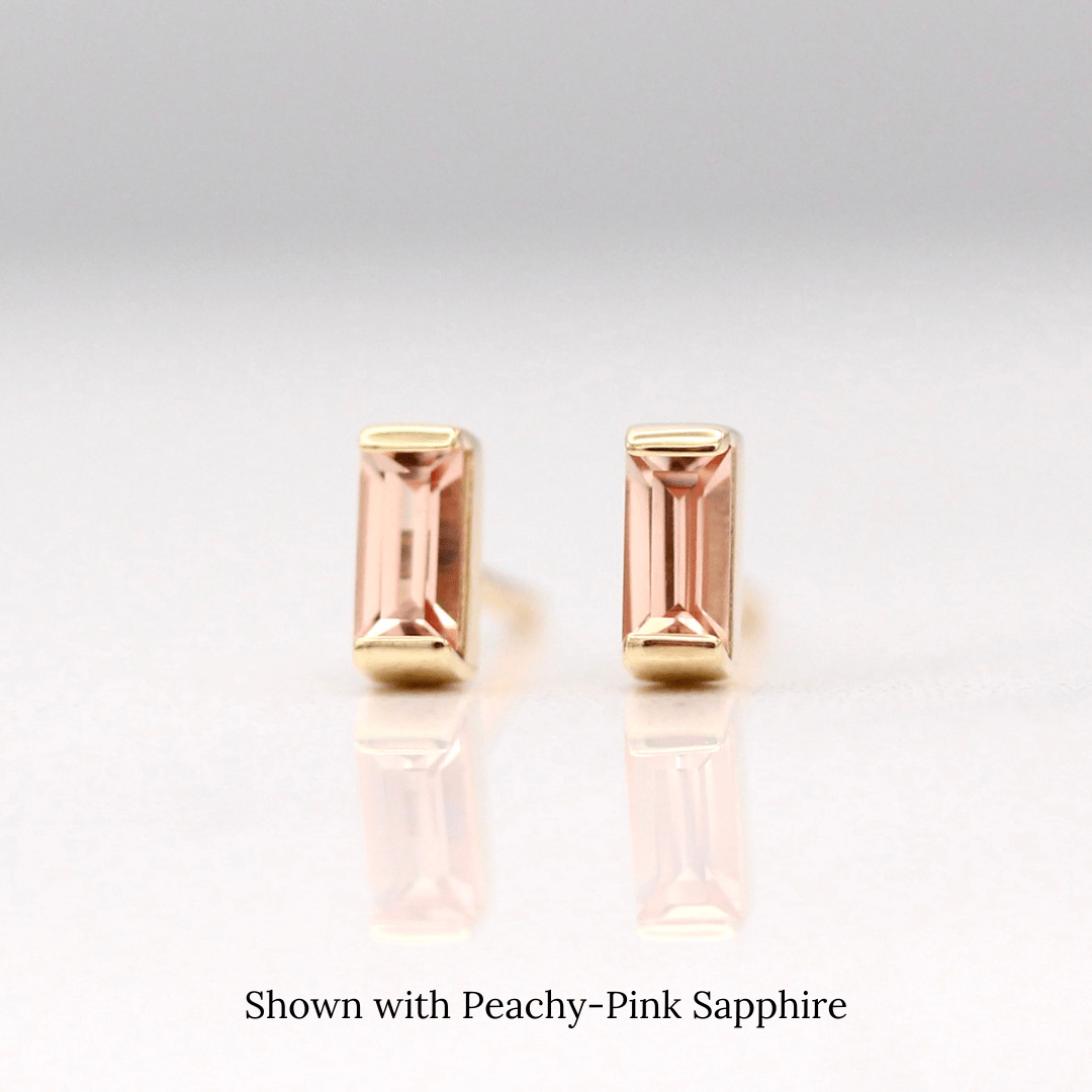 The October Baguette Birthstone Earrings with Peachy-Pink Sapphire in Yellow Gold against a white background
