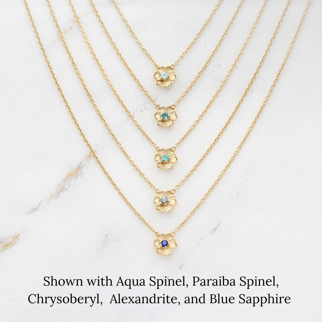 The March Birthstone Poppy Necklace with Aqua Spinel in Yellow Gold stacked with the December Birthstone Poppy Necklace with Paraiba Spinel in Yellow Gold, the August Birthstone Poppy Necklace with Chrysoberyl in Yellow Gold, 
 the June Birthstone Poppy Necklace with Alexandrite in Yellow Gold, and the September Birthstone Poppy Necklace with Blue Sapphire in Yellow Gold against a white background
