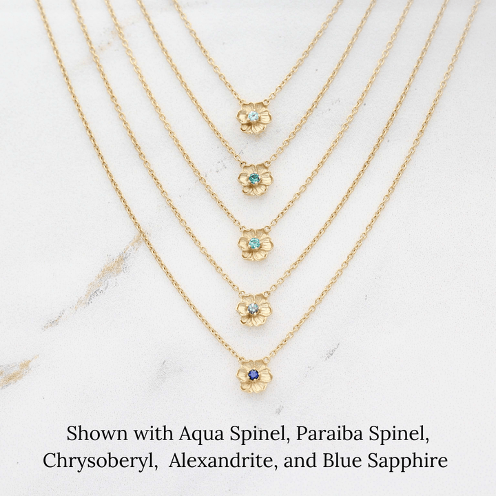 The March Birthstone Poppy Necklace with Aqua Spinel in Yellow Gold stacked with the December Birthstone Poppy Necklace with Paraiba Spinel in Yellow Gold, the August Birthstone Poppy Necklace with Chrysoberyl in Yellow Gold, 
 the June Birthstone Poppy Necklace with Alexandrite in Yellow Gold, and the September Birthstone Poppy Necklace with Blue Sapphire in Yellow Gold against a white background
