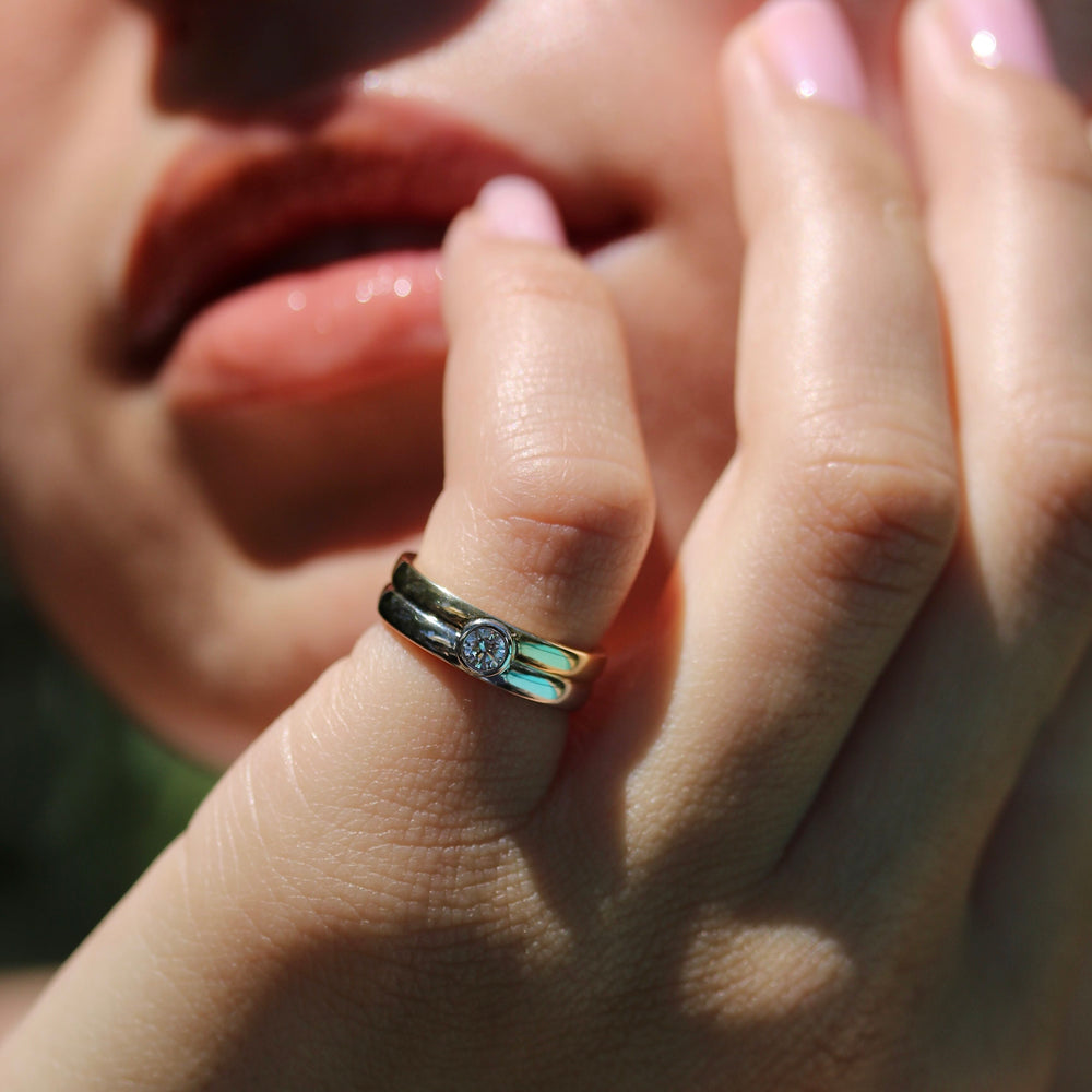 two tone yellow and white gold bubble ring with bezel set round diamond on a hand