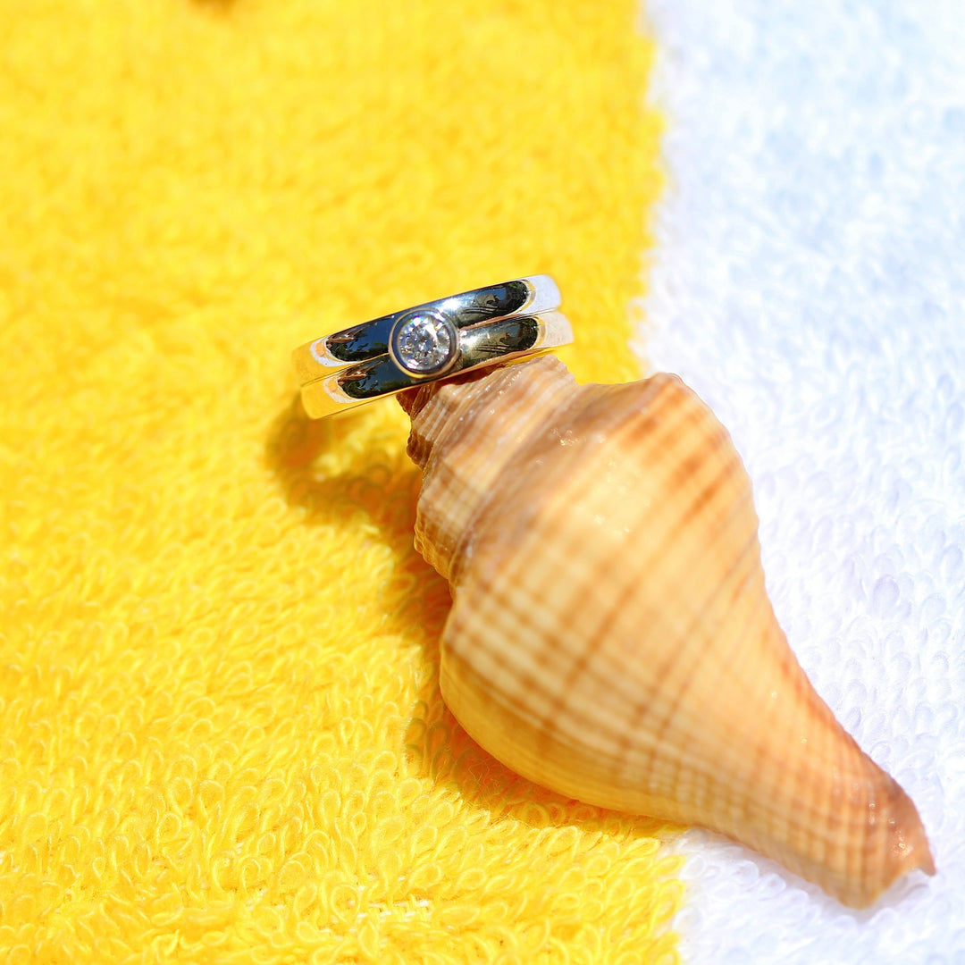 Two tone gold ring with a diamond on a seashell against a yellow and white background