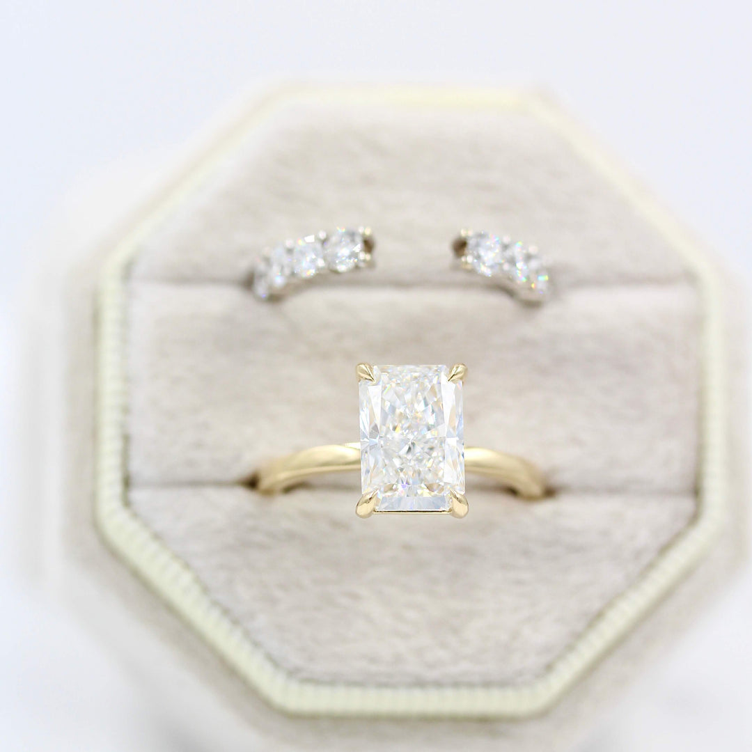 The Celeste Ring (Radiant) in Yellow Gold in a tan velvet ring box with the Open Lexington Wedding Band in white gold