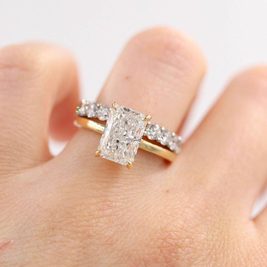 The Celeste Ring (Radiant) in Yellow Gold stacked with the Open Lexington Wedding Band in white gold modeled on a hand