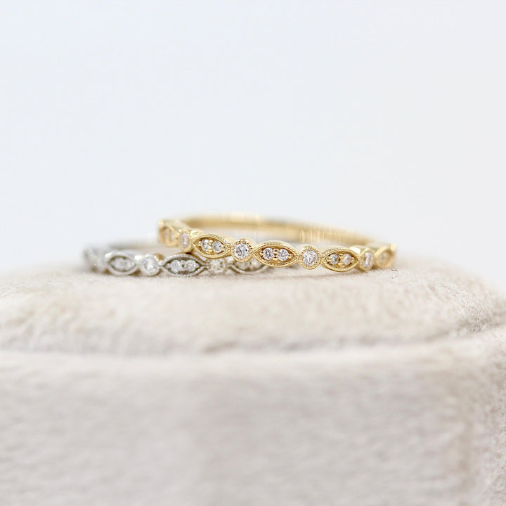 The Charlotte Wedding Band in Yellow Gold and The Charlotte Wedding Band in White Gold stacked on a ring box