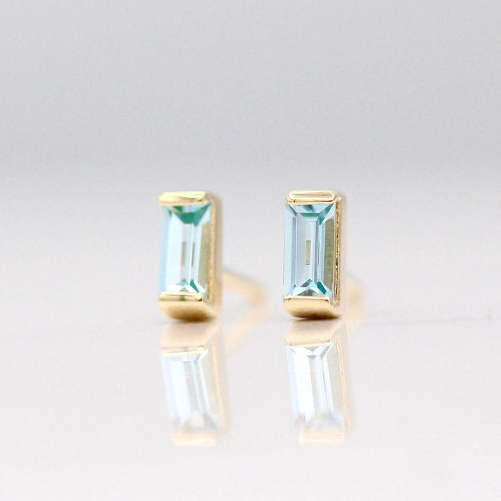 The March Baguette Birthstone Earrings with Aqua Spinel in Yellow Gold against a white background