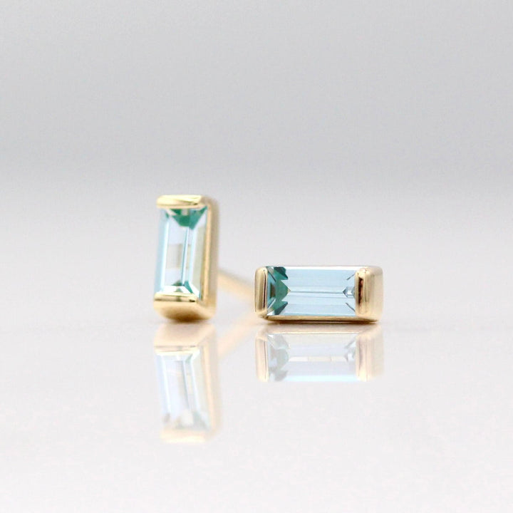The March Baguette Birthstone Earrings with Aqua Spinel in Yellow Gold against a white background