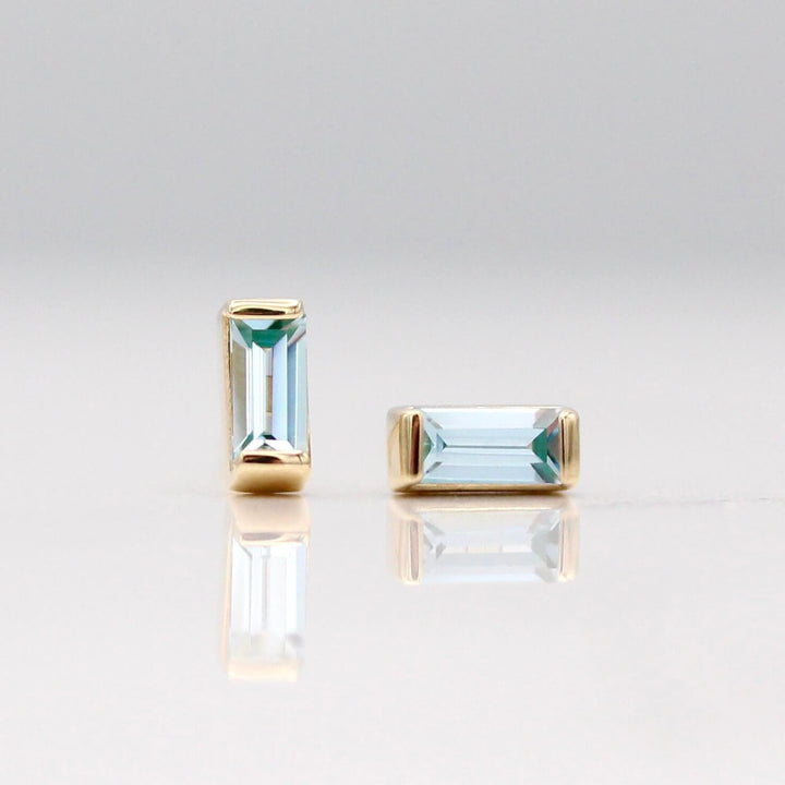 The March Baguette Birthstone Earrings with Aqua Spinel in Yellow Gold against a white background