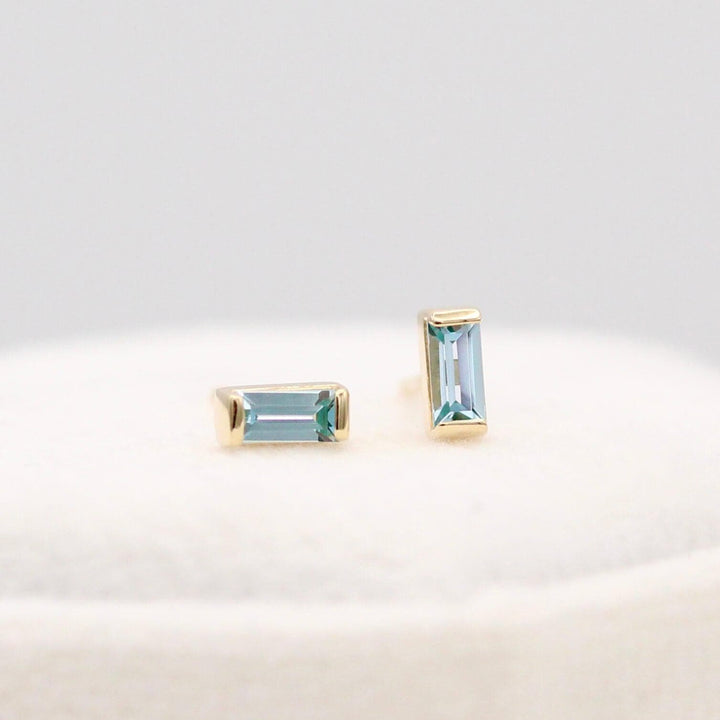 The March Baguette Birthstone Earrings with Aqua Spinel in Yellow Gold atop of a white velvet ring box